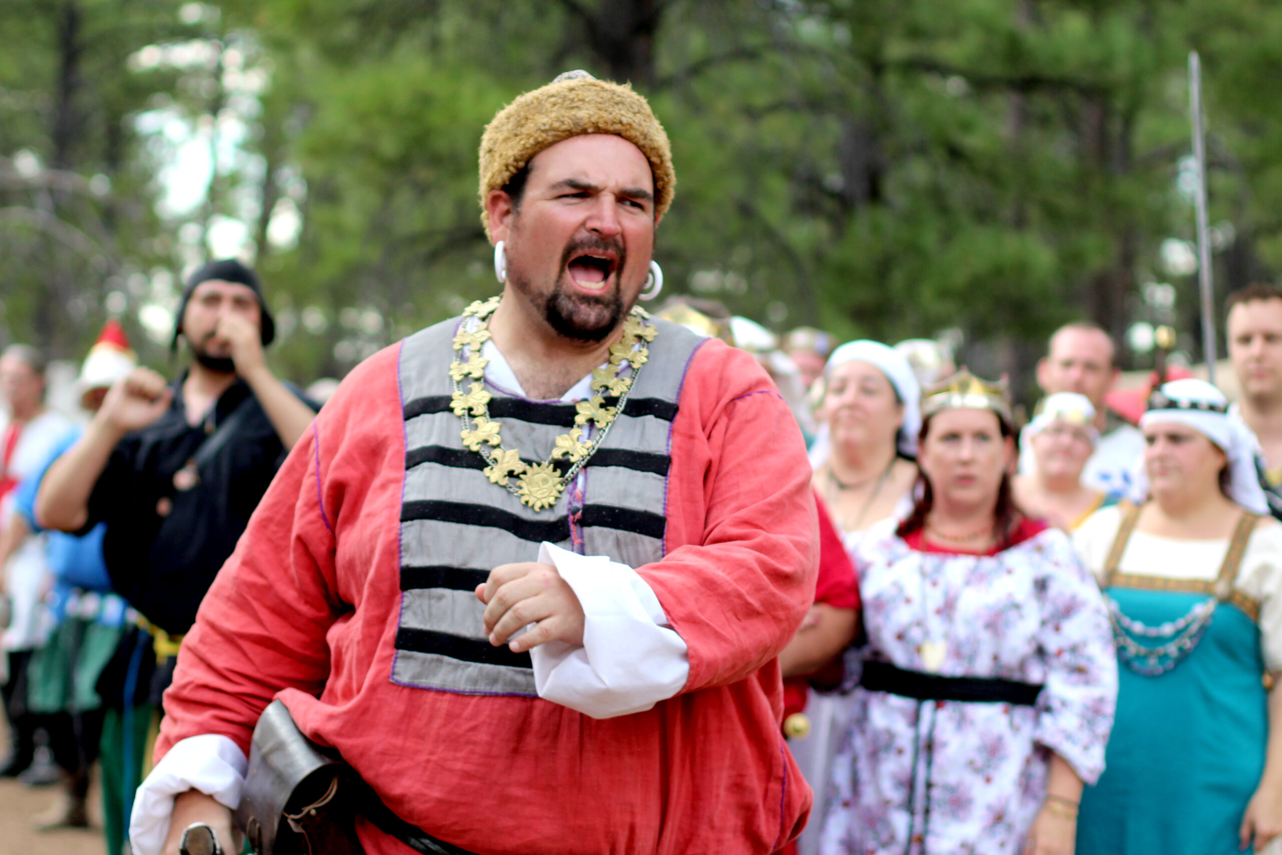 A populace member in Rus style garb speaks to the populace at large with veracity, heralding the event.